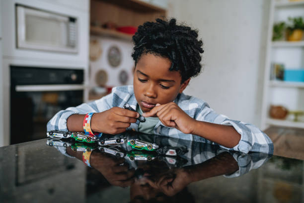 A close-up of a child playing with toy cars flipped upside down.